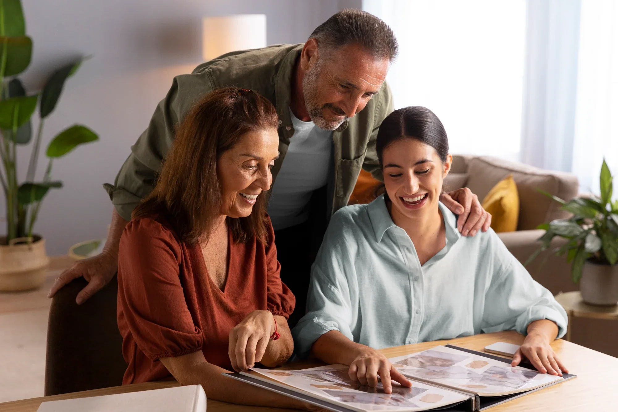 Three generations of a family looking through a photo album together at the dining table